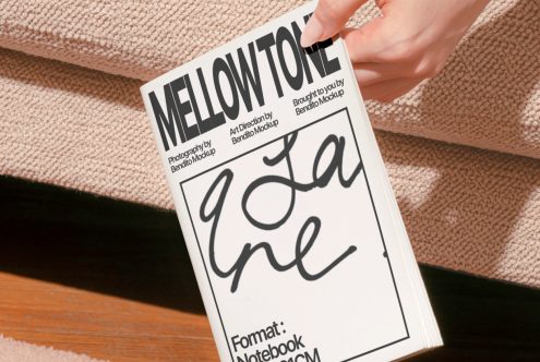 Hand holding a magazine mockup with Mellowtone cover design on textured background, showcasing script font, print template for designers.