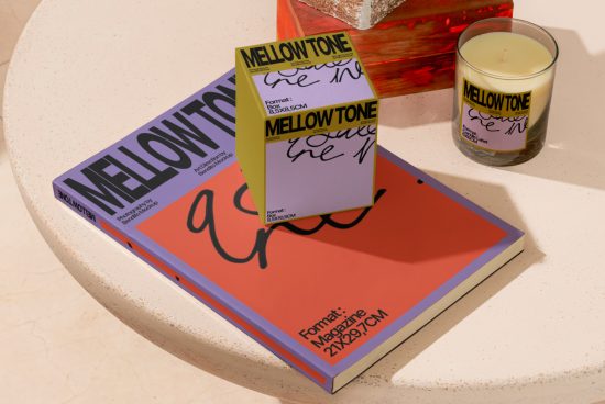 Magazine mockup on a table with candle accessory, showcasing modern fonts and vibrant graphics, ideal for design presentation.