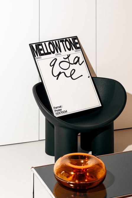 Poster mockup on black chair with orange glass bowl, minimalist layout