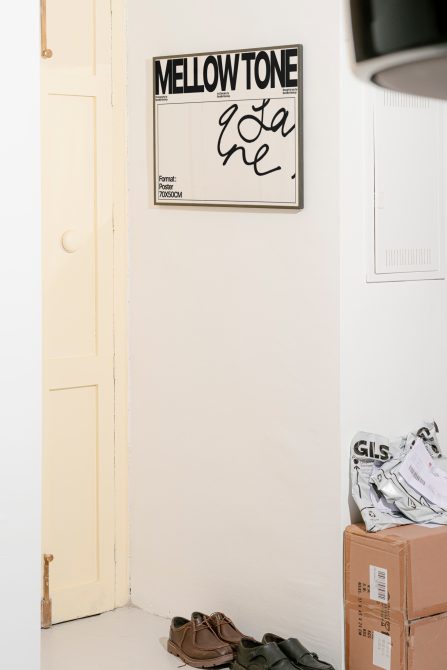 Interior mockup scene with poster featuring bold font, wall, door, shoes, and parcels, ideal for showcasing typography or graphic designs.