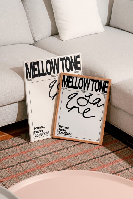 Two Mellow Tone poster frames on living room floor by cream sofa