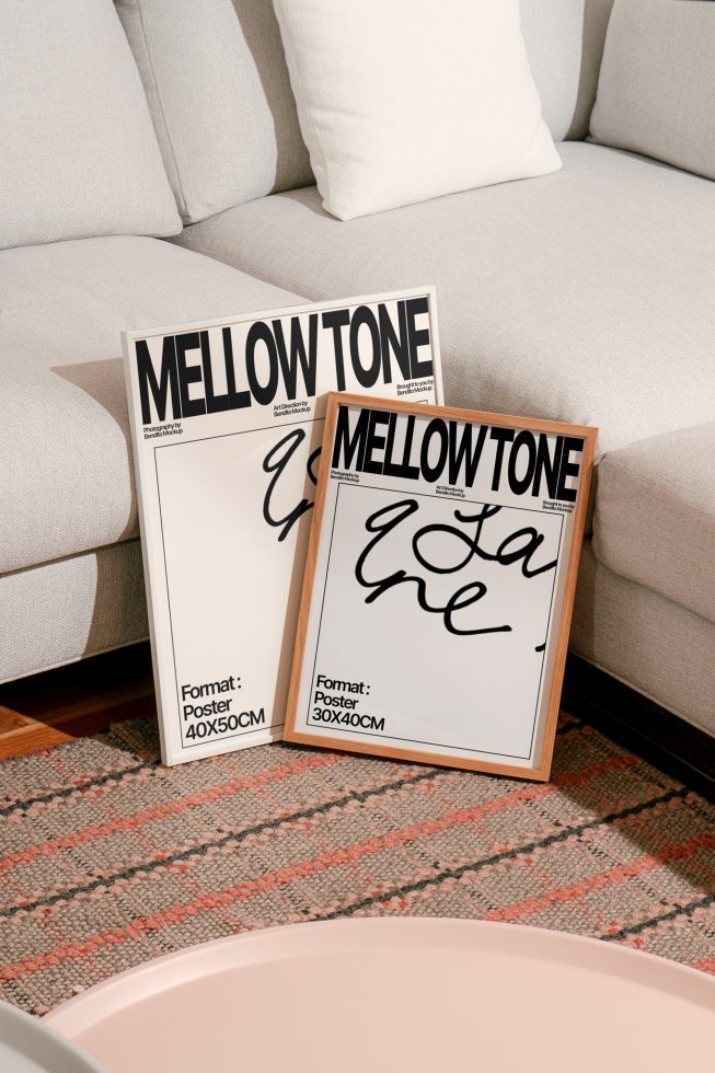 Elegant poster mockups in wooden frames leaning against a couch with decorative pillows, showcasing stylish font design for home decor.