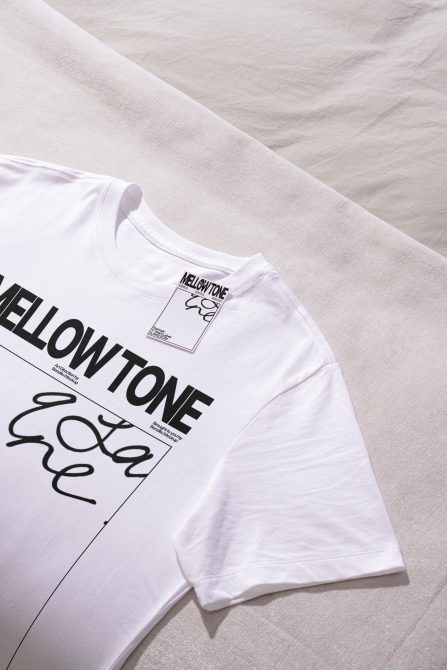 Folded white t-shirt displaying Mellow Tone print on natural linen background