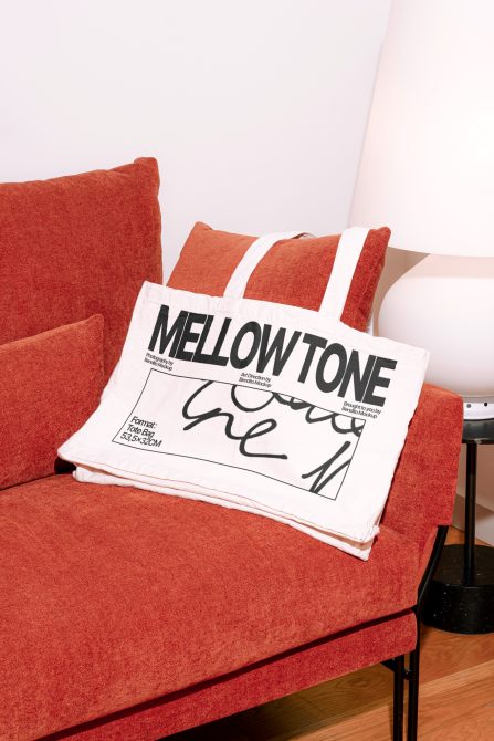 Elegant tote bag mockup on red sofa, modern design presentation, digital asset for professional graphics and templates.