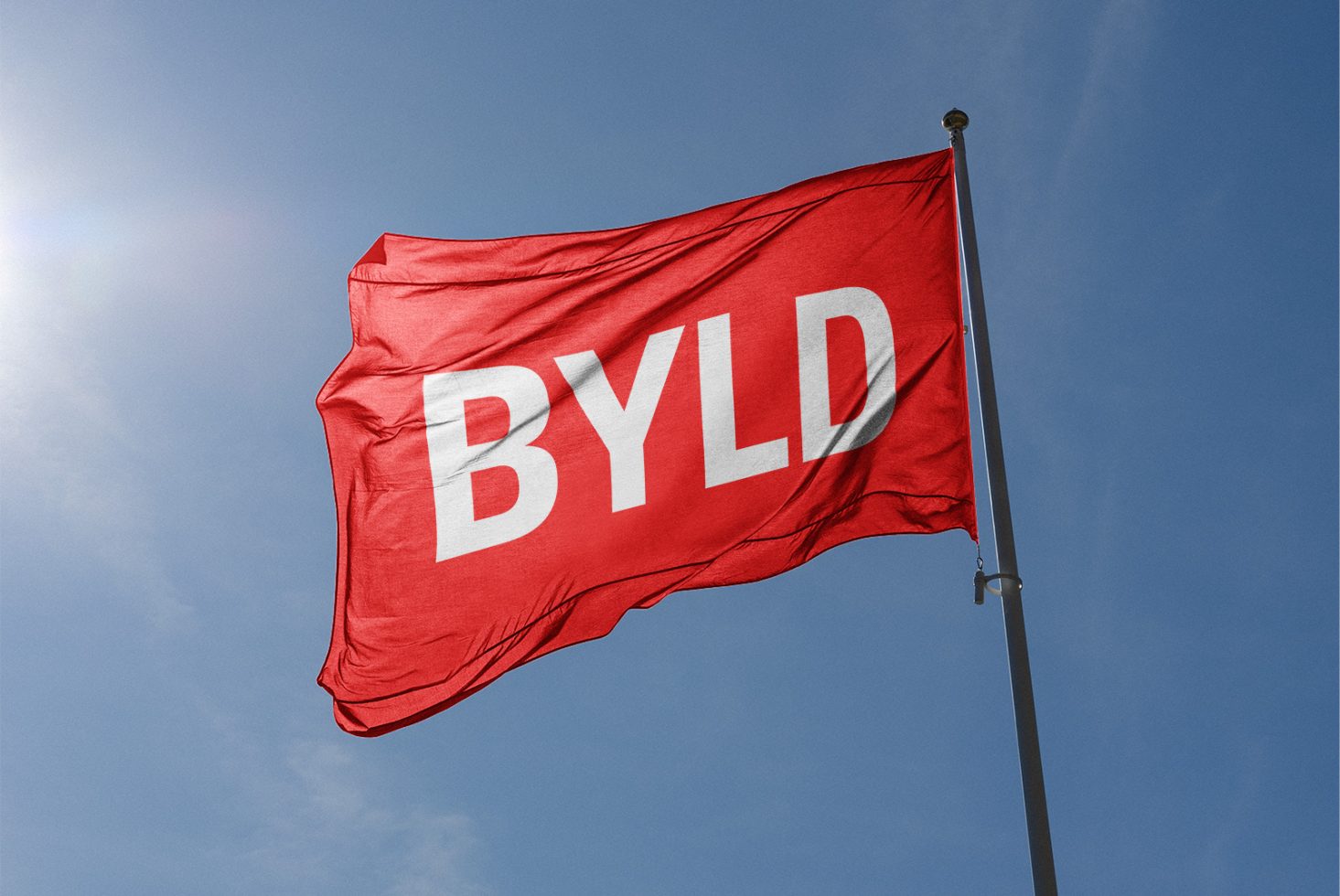 Red flag mockup with customizable logo waving against a clear blue sky, perfect for branding, graphic design, and advertising presentations.