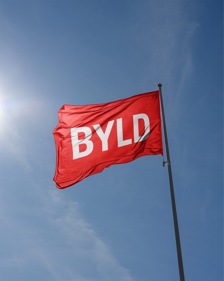 Red flag with bold white text flying against a clear blue sky, ideal for mockup designs, advertising, and branding materials.