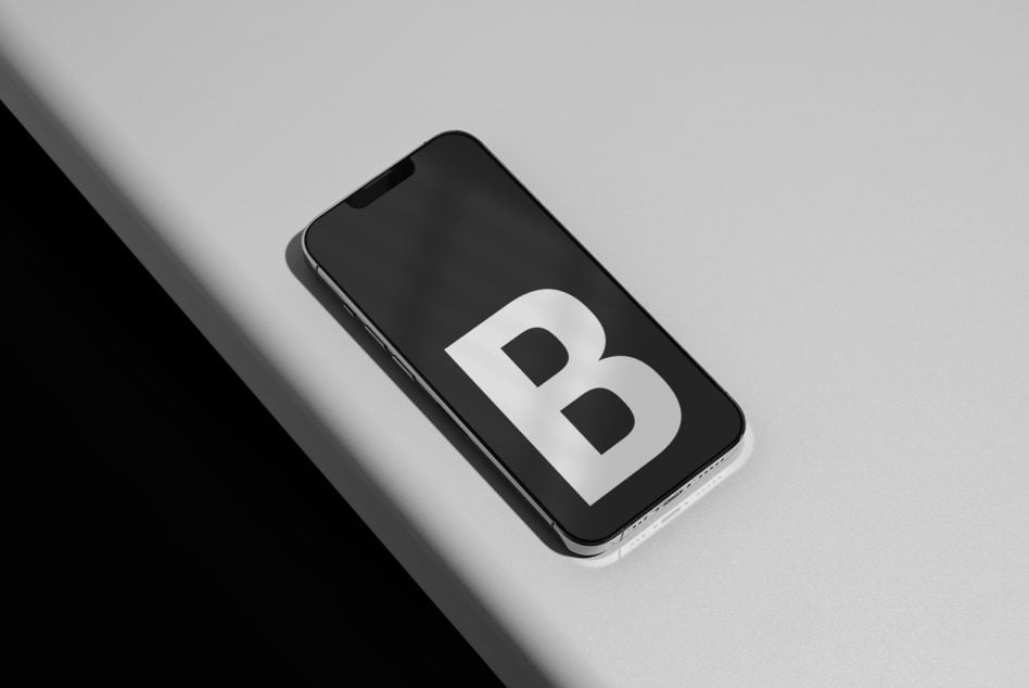 iPhone mockup with large white letter B on black screen, diagonal angle