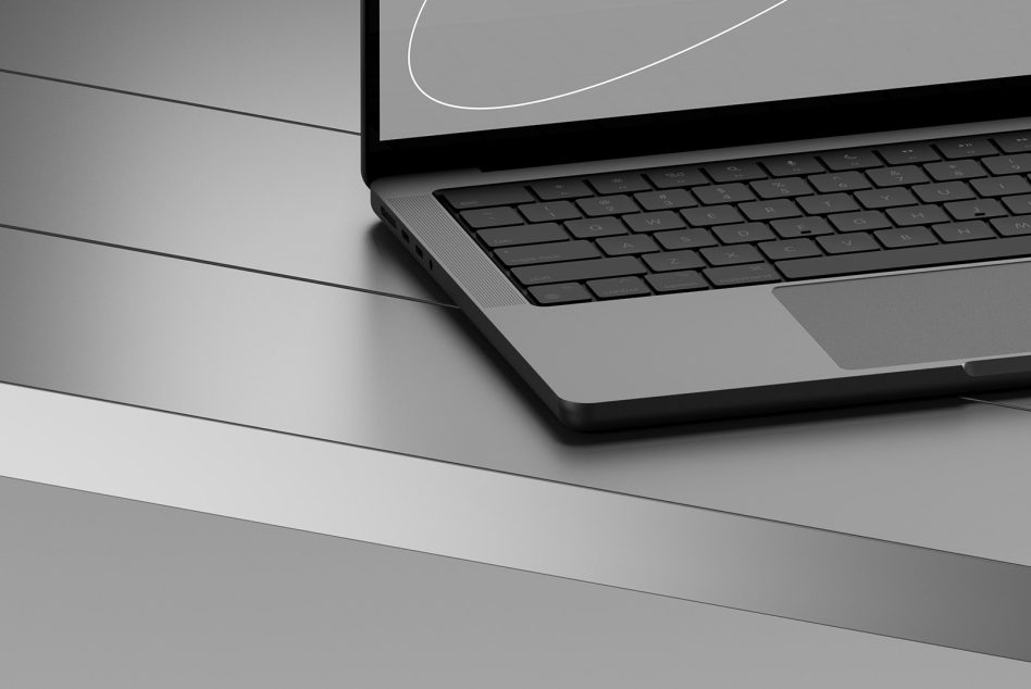 Modern laptop mockup on gray slanted surface, sleek design with partial keyboard view, perfect for digital asset templates.