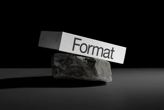 Creative mockup of box balanced on rock with the word Format, ideal for packaging design presentation, isolated on dark background.