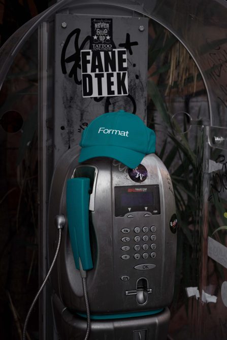 Vintage public payphone wearing teal Format cap with handset in matching color