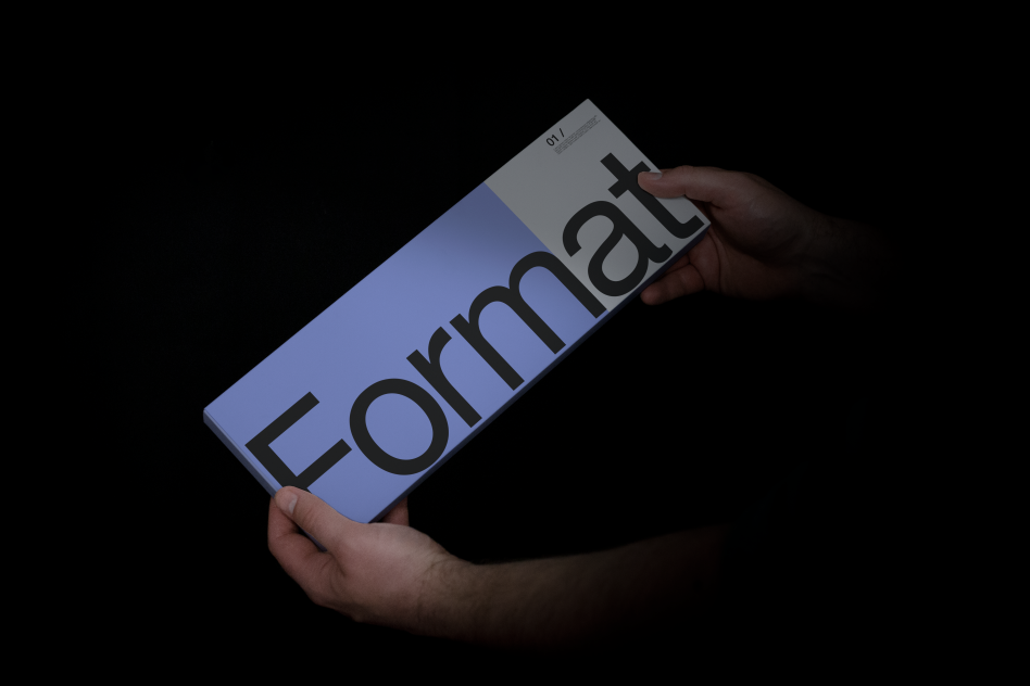 Hands holding a magazine mockup with the word Format on cover, against a dark background, ideal for design presentations.