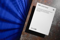 White A4 letterhead with Grid 02 label on rusty metal surface, blue fabric backdrop