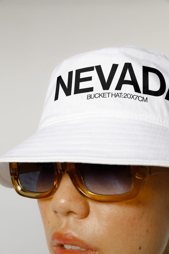 Close-up of a white bucket hat with bold text design paired with stylish sunglasses for fashion mockup.