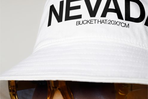 Close-up of white bucket hat with bold text, part of person's face with sunglasses visible, for fashion mockup designs.