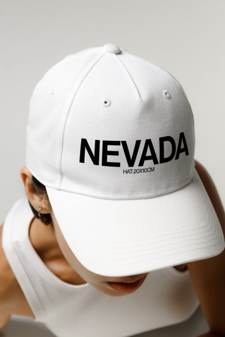 Close-up view of a white cap with "NEVADA" text, worn by a person, suitable for mockup design assets for branding and fashion projects.