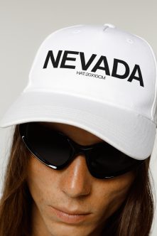 Woman wearing white baseball cap with Nevada print facing camera