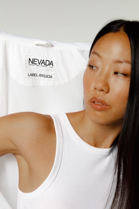 Woman wearing white ribbed tank showing Nevada label 8x5.5cm on back shoulder