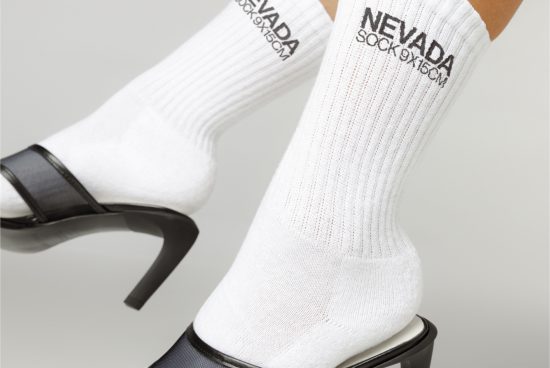 Close-up view of white crew socks with black text branding mockup paired with high heels for fashion design presentations.