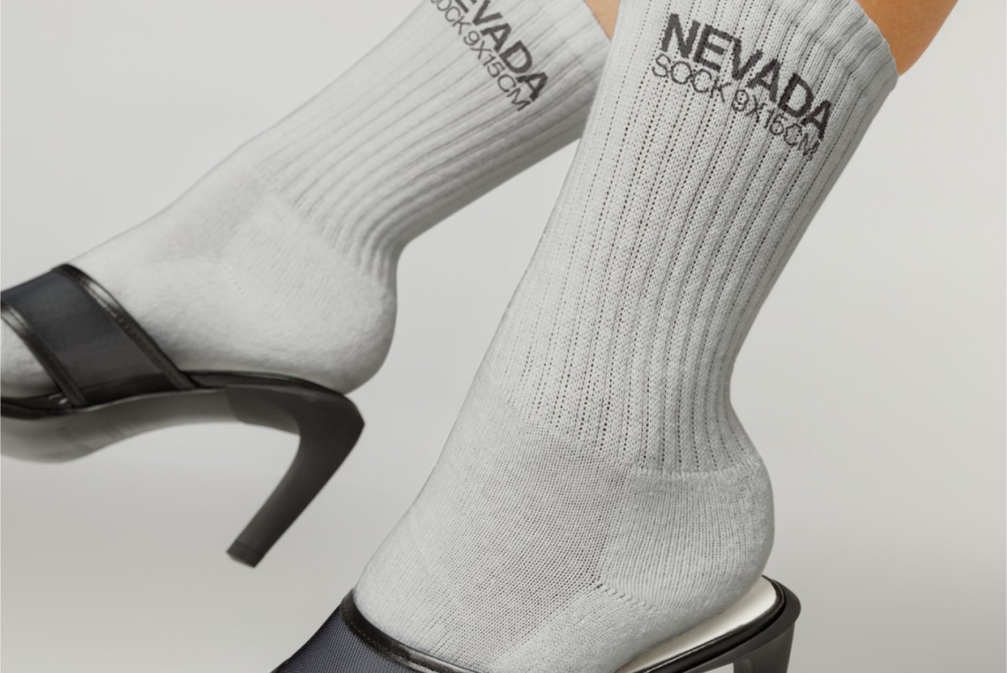 Close-up of gray ribbed socks with black text design on a person wearing high heels, perfect for fashion mockups or apparel templates.