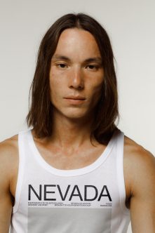 Person wearing white tank top with Nevada branding, looking down slightly