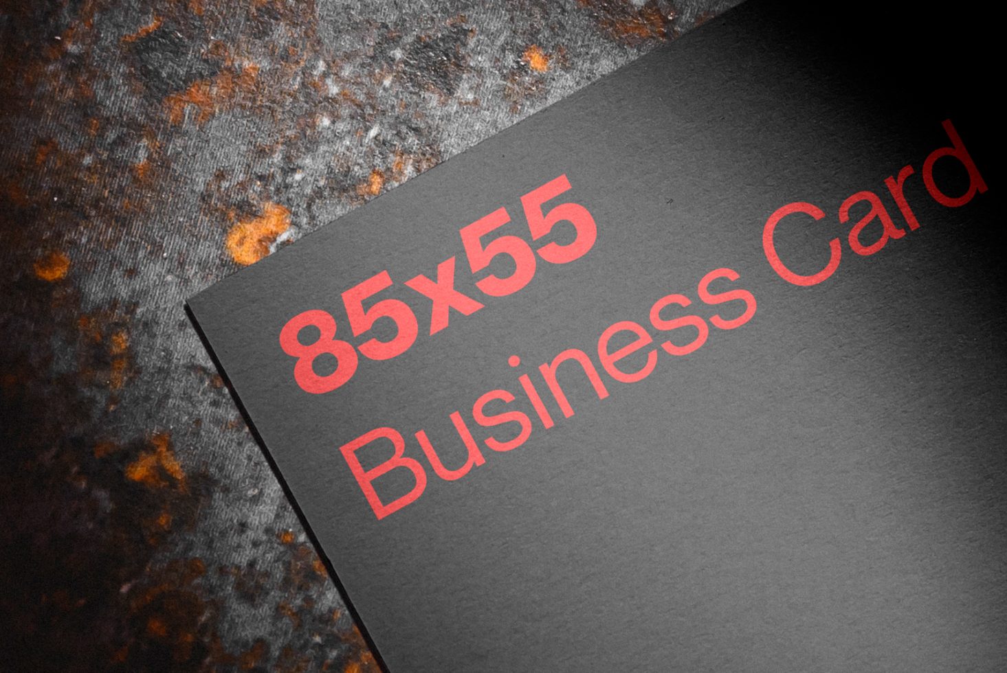 Mockup of a black 85x55 business card with red lettering on textured background, perfect for branding and stationery design presentations.