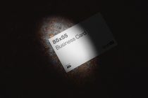 Minimalist white business card showing 85x55 dimensions on dark rusty background