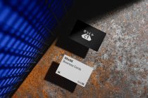 Business card mockup showing white card with blue variant against industrial backdrop