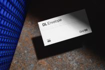 White DL envelope mockup showing open flap detail on weathered metal background