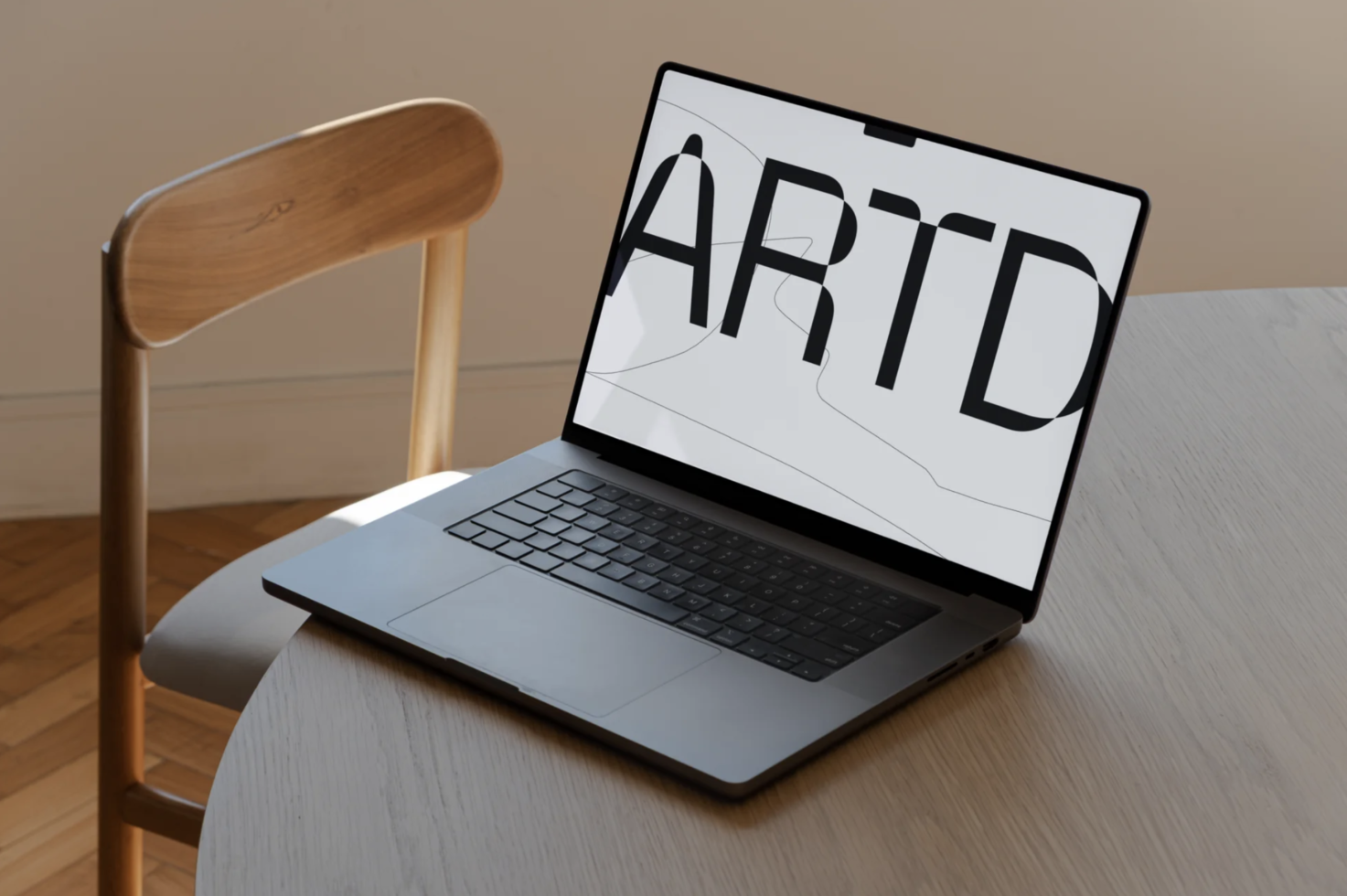 Modern laptop on desk displaying bold ARTD text, ideal for font showcase, graphic design, and device mockup for presentations.