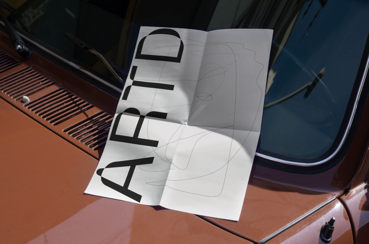 Printed paper with bold typography mockup on a vintage car dashboard in sunlight, showing design contrast and shadow play for designers.