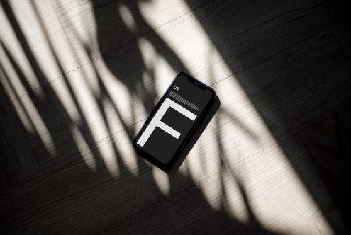 Smartphone mockup on wooden floor with dramatic lighting and shadow play, perfect for showcasing app designs and interfaces for digital assets.