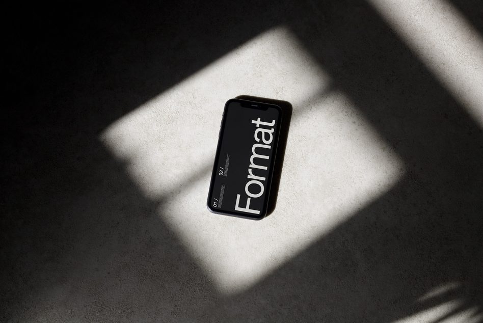 iPhone mockup withFormat text on black screen in sunlit space