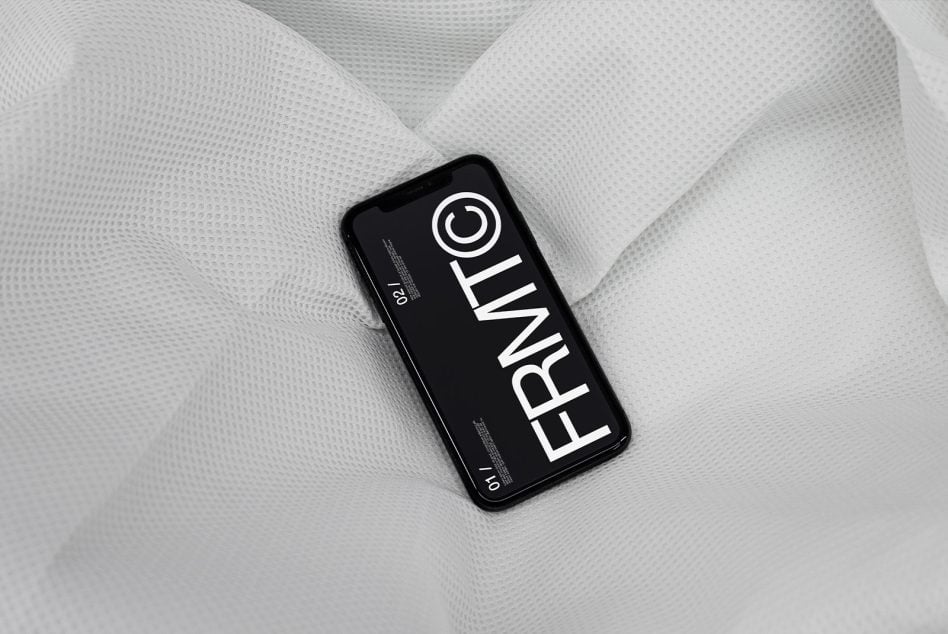 Dark phone mockup on soft white crinkled textile with minimalist layout