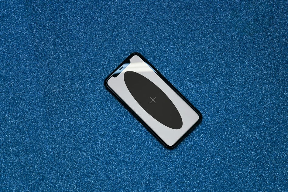 iPhone mockup with black frame on sparkly blue textured background, centered shot