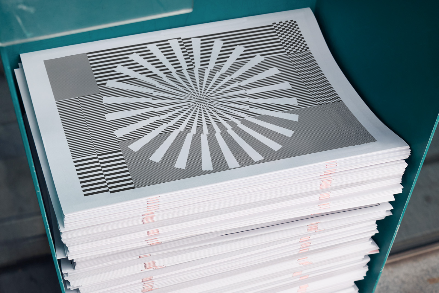 Stack of printed graphic design patterns on paper sheets, showcasing geometric black and white radial lines for creative mockup inspiration.