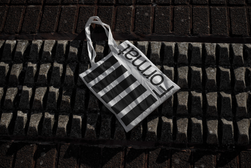 Stylish tote bag mockup with bold typography design on textured cobblestone background, perfect for fashion and retail branding.