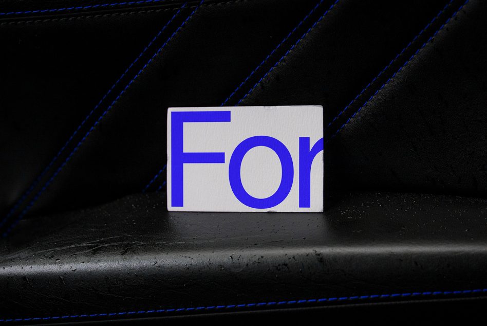 Blue and white typography card mockup on textured black seat with contrast stitching, perfect for font or logo display for graphic designers.