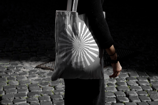 Stylish tote bag mockup with geometric pattern design, held by a person on cobbled street, ideal for presentations and product display.
