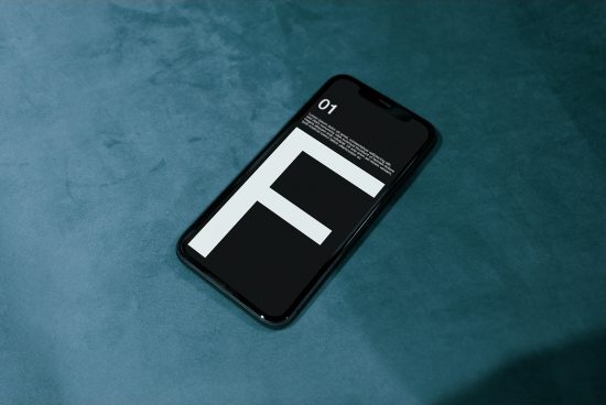 Smartphone mockup on a textured blue surface showcasing a bold typeface for app design, ideal for designer presentations and digital mockups.