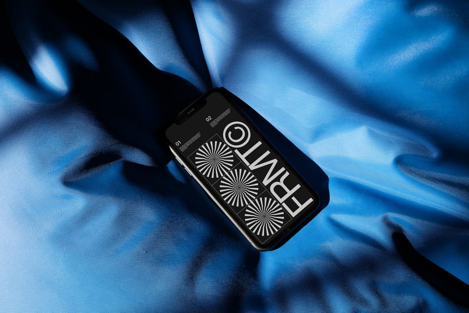 Phone displaying sunburst graphics on flowing blue fabric with light