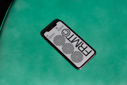 Smartphone on green surface displaying black and white graphic design, ideal for Mockup category in digital asset marketplace.