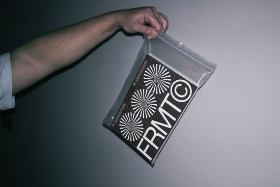 Hand holding clear plastic envelope with black and white patterned graphic design print, showcasing design presentation and packaging mockup.
