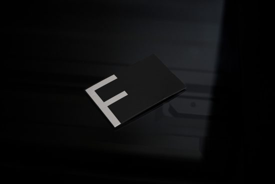 Elegant black business card with white letter F design mockup on a dark reflective surface, perfect for branding and identity projects.