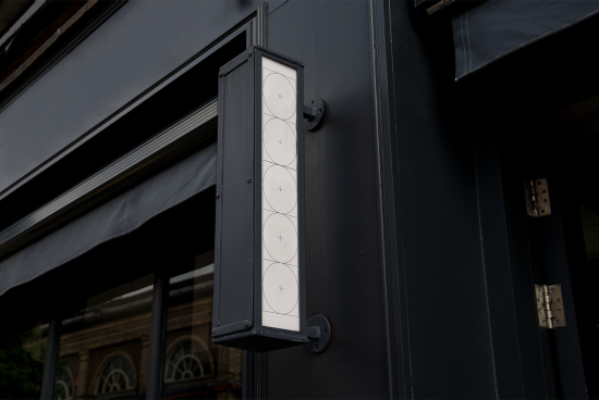 Elegant outdoor vertical lightbox mockup on dark storefront, ideal for branding and signage designs.