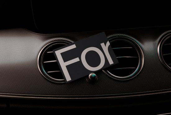 Luxury car dashboard mockup featuring closeup of elegant air vents with a card displaying the word For, ideal for presentations and branding.
