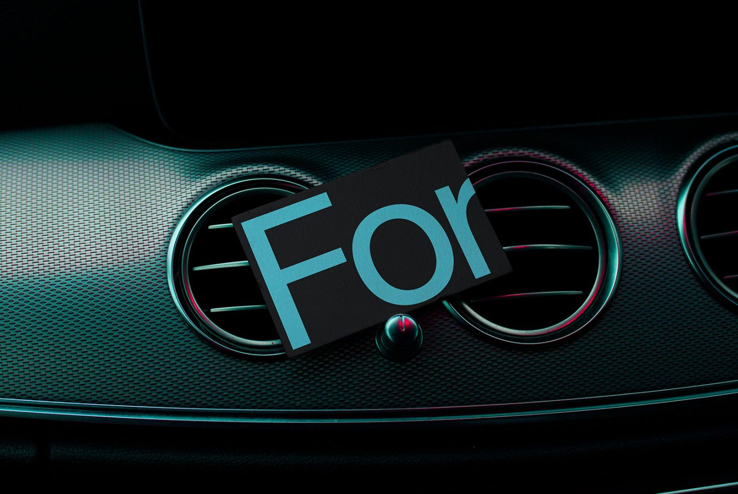 Elegant car dashboard mockup featuring sleek vents and a carbon fiber texture with the word For on a card, ideal for automotive design projects.