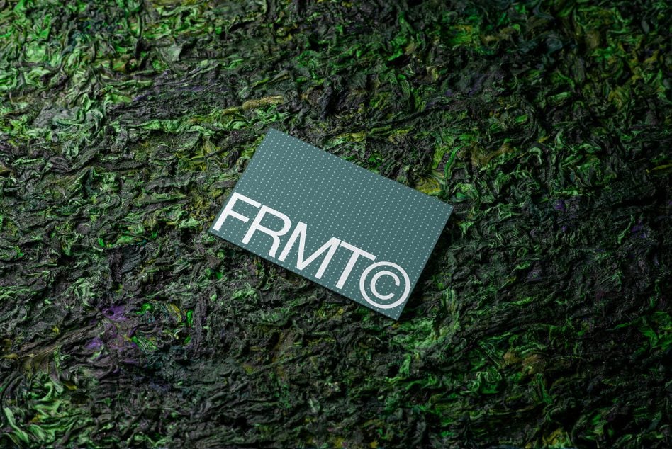 Business card on textured moss green bark background with FRMTC brand logo