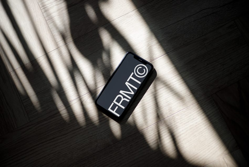 Smartphone mockup on wooden floor with dramatic lighting and shadows, ideal for presenting app designs and screen interfaces to clients.