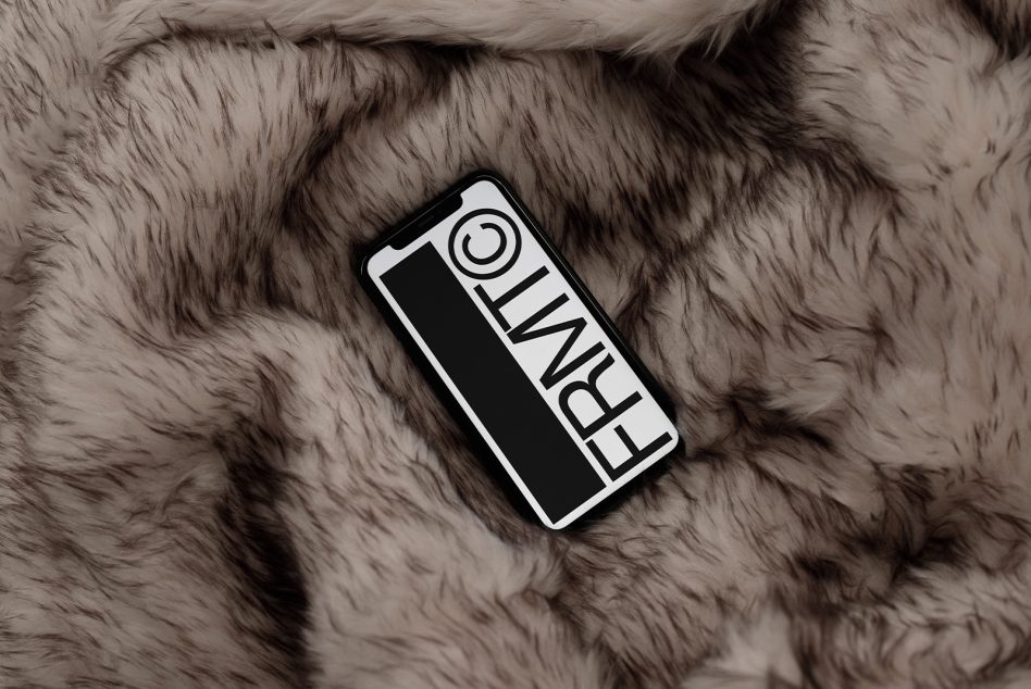 White phone displaying FRNWL branding on soft beige fur texture