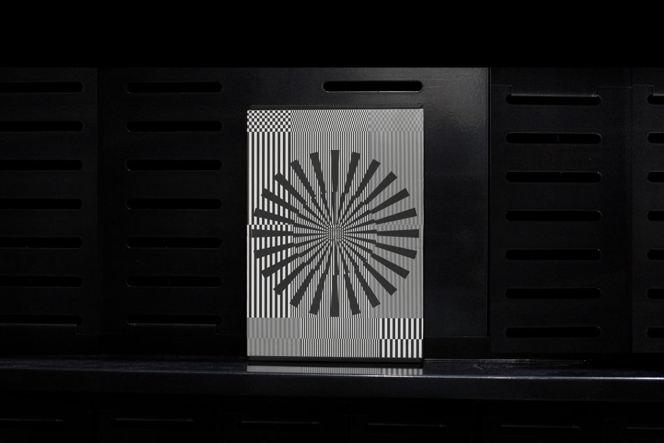 Abstract geometric graphic design on sleek metal card mockup with radial pattern, showcased on a dark modern vent background ideal for brand presentation.